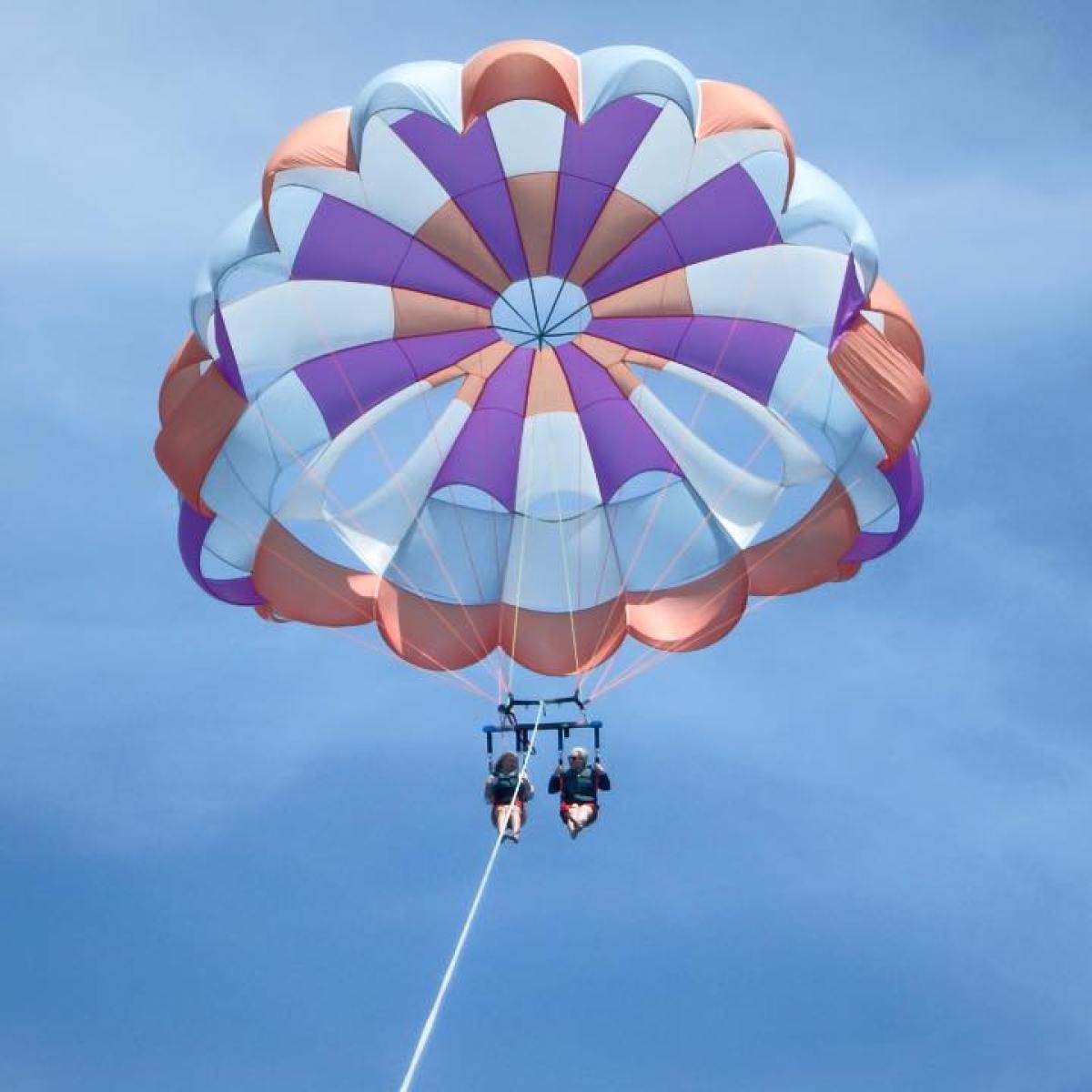 Two people flying in a pink blue purple parasail