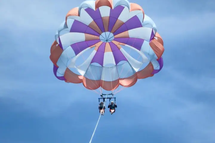 Two people flying in a pink blue purple parasail
