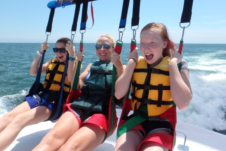 Three ladies taking flight in a parasail