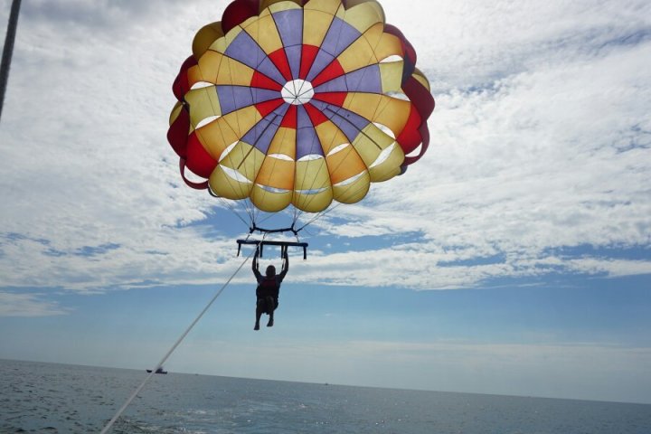 A silhouette of a man flying with a colorful parasail